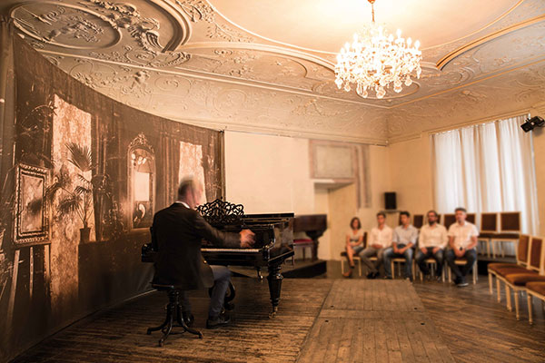 Mann spielt am Klavier und die Zuhörer lauschen der Musik