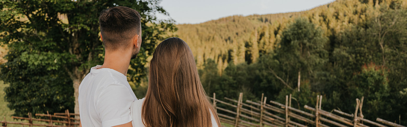 Junges Pärchen, von hinten fotografiert, schaut in die Landschaft.